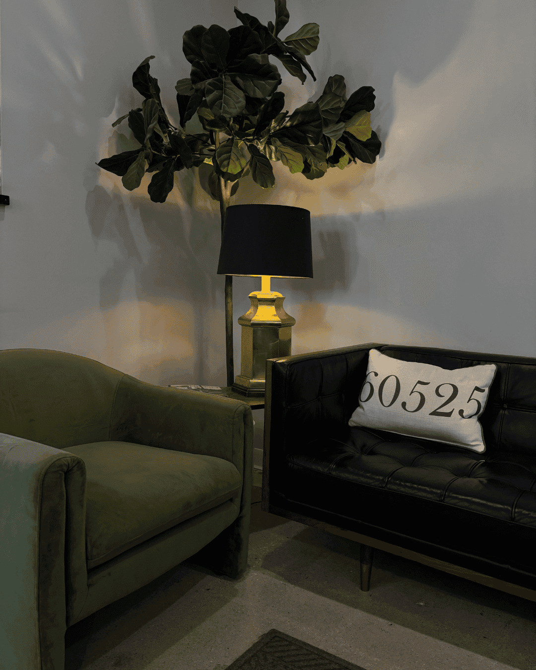 Cozy living area with green chair, black couch, and lamp. Pillow shows "80525".