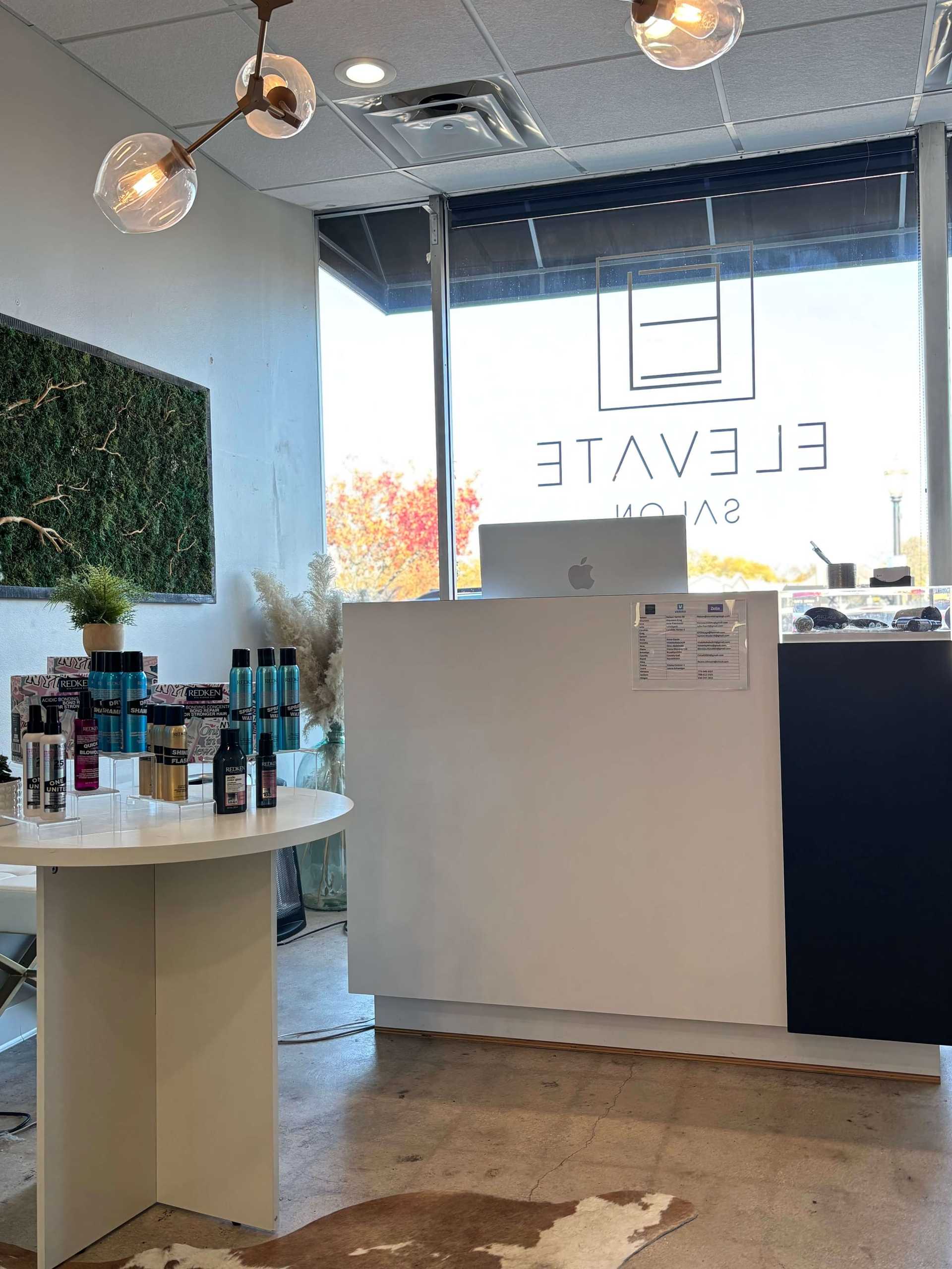 Elevate Salon reception area with modern decor and hair products displayed on a round table.