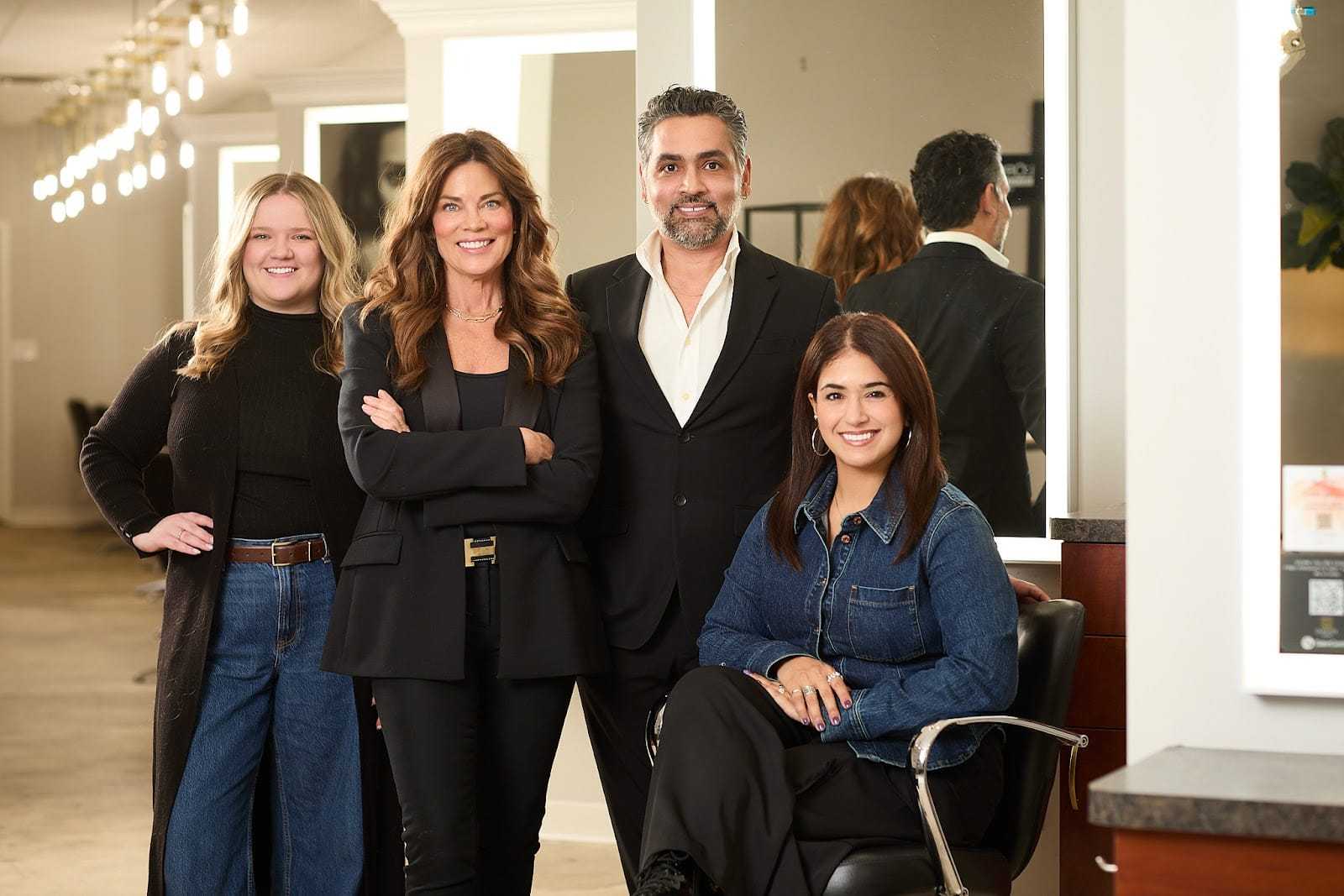 Group of four people in a salon, smiling and posing together.